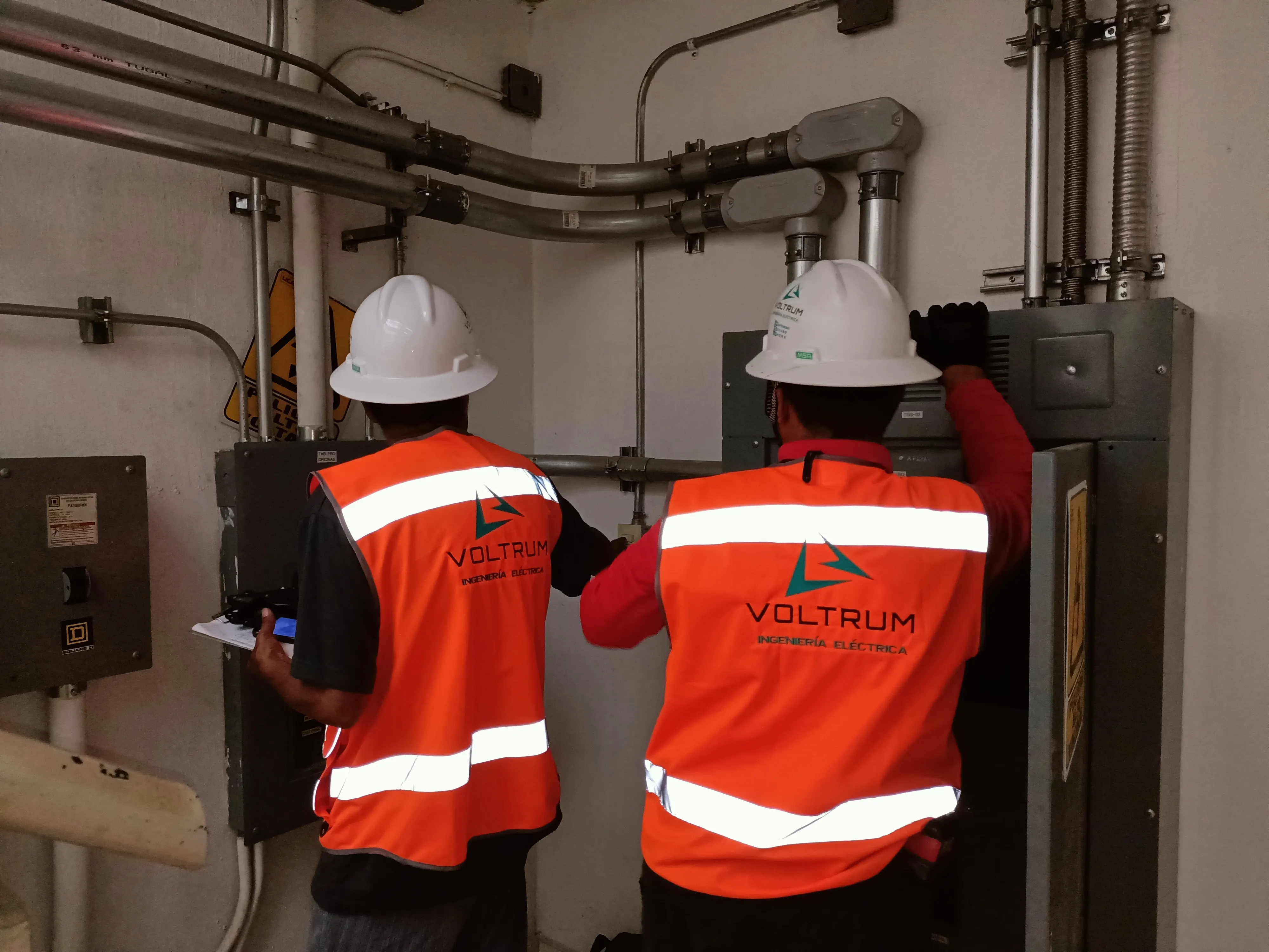 Técnicos de VOLTRUM® con uniforme de la empresa trabajando en un tablero eléctrico